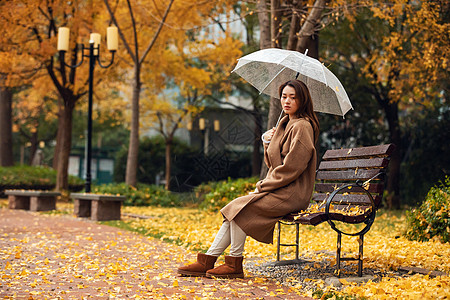 秋季雨天美女公园撑伞背景图片