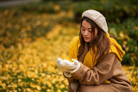 女性秋季文艺美女手捧银杏叶背景