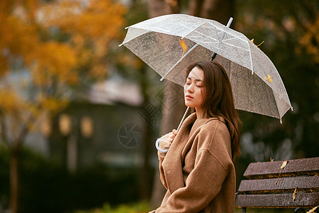 秋季雨天美女银杏落叶撑伞背景图片