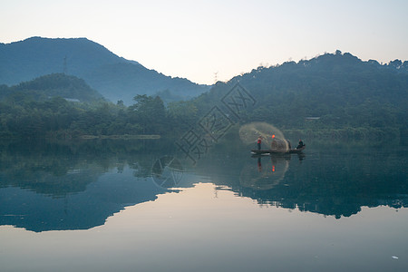 渔夫撒网湖南郴州东江湖上撒网的老年渔夫和船背景