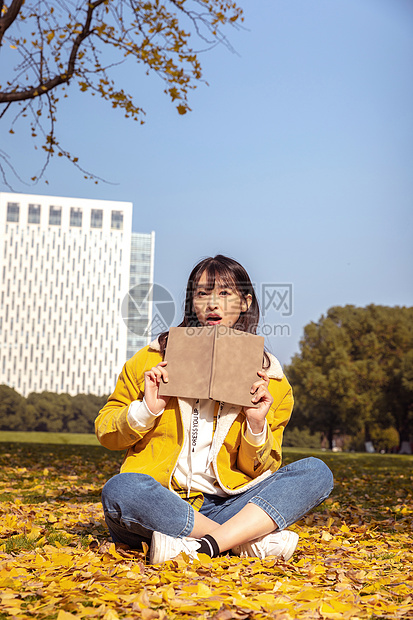 坐在满地银杏叶下的甜美女孩形象图片