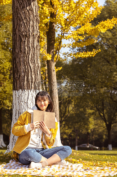 倚靠在银杏树下看书的女孩图片