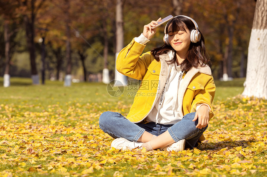 坐在满地银杏叶下听音乐的女孩图片