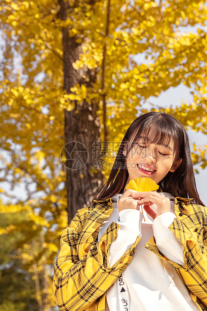 银杏树下手捧银杏叶的女孩图片