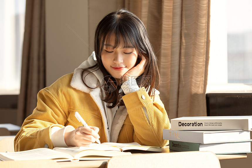 高清照片下载,该高清照片标题为坐在教室写作业的女大学生,编号