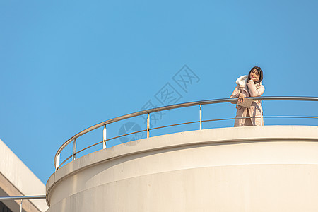 大学趴在天台栏杆前的甜美女孩背景