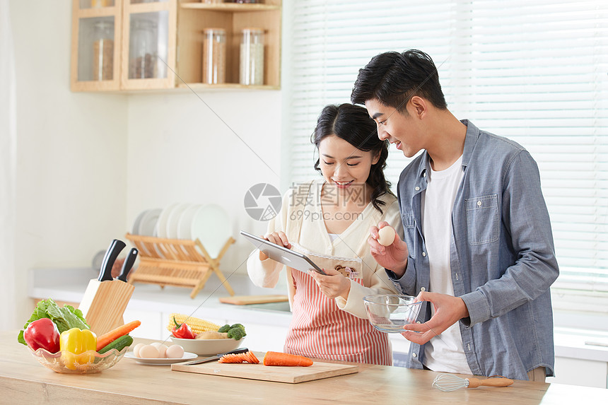 年轻夫妻在厨房线上学习做菜图片