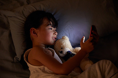 女生夜晚玩手机小女孩躺在床上玩手机背景