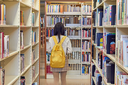 女学生在图书馆书架找书背影图片