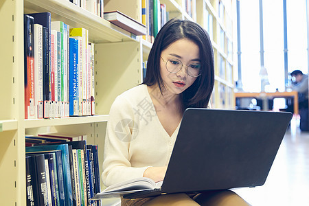 年轻女士在图书馆用笔记本电脑学习图片