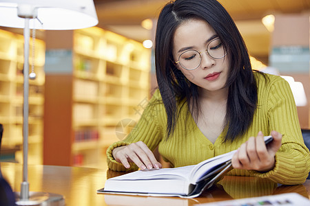 年轻女学生在图书馆看书图片