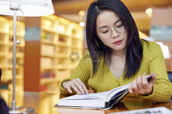 年轻女学生在图书馆看书图片