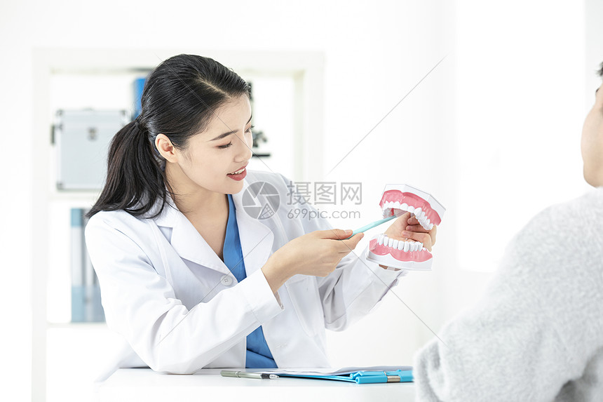 女性牙齿医生拿着假牙给病人讲解图片