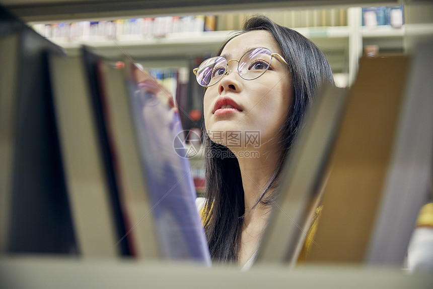 年轻女学生在图书馆找书图片