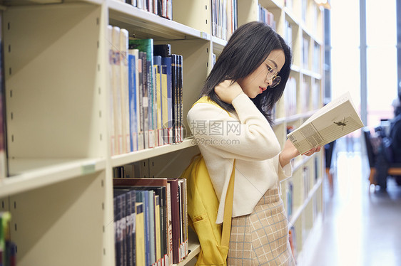 年轻女学生在图书馆看书图片