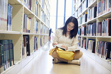 年轻女学生在图书馆看书图片