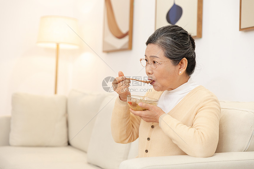 老奶奶坐沙发上喝银耳汤图片