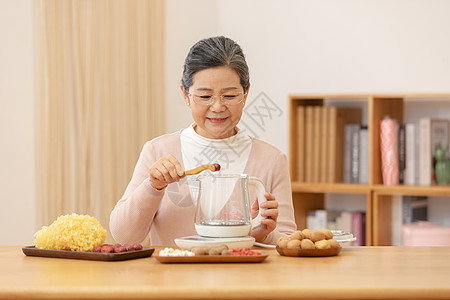 老人健康老奶奶居家养生煮银耳汤夹红枣特写背景