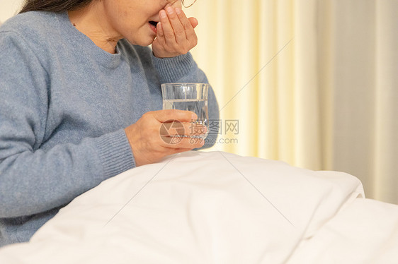 老年人躺床上喝水吃药特写图片