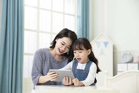 妈妈指导女儿用平板电脑在家上课背景