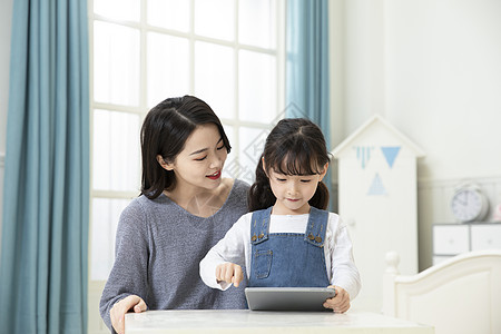 上学小女孩妈妈指导女儿用平板电脑在家上课背景