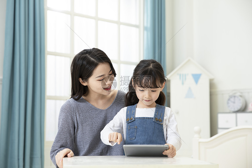 妈妈指导女儿用平板电脑在家上课图片