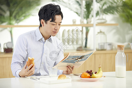 年轻男士吃早餐看报纸高清图片