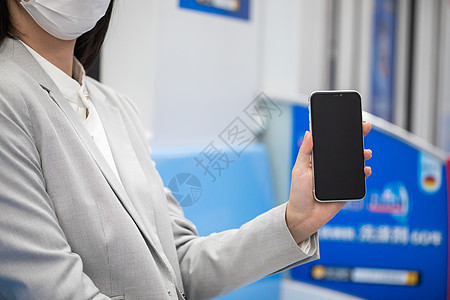 戴口罩的女性坐地铁展示手机特写图片