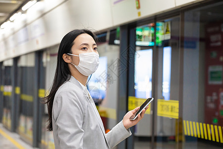 戴口罩的女人戴口罩的女性拿手机等地铁背景