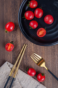 黑色餐盘上红色的番茄叉子筷子图片