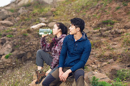 跪坐着男女野外徒步坐着休息喝水的情侣背景