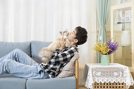 坐在沙发上抱着猫的男孩图片