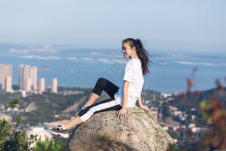 坐山顶户外坐石头上面的美女背景