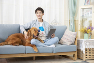在沙发使用平板电脑的男孩与狗相伴图片