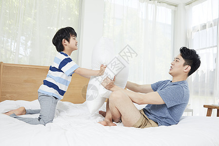 年轻爸爸和孩子在床上玩耍图片
