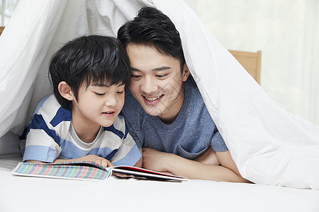 一起看书的父子年轻爸爸陪儿子一起看书背景