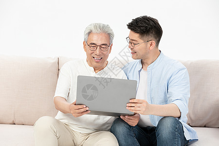 孝顺中老年父子沙发上看笔记本电脑背景