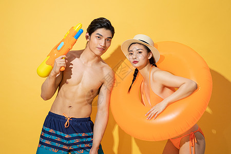 游泳圈和海鸟夏日泳装情侣拿着水枪和游泳圈背景