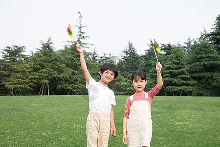 户外手举风车的男孩女孩图片