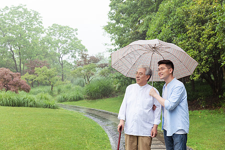 老年人锻炼中老年父子撑伞下雨天逛公园背景