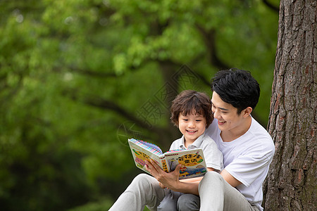 可爱人物父子在公园里看童话故事书背景