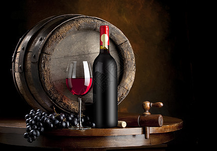放在酒窖橡木桶前的红酒和盛有红酒的红酒杯背景图片