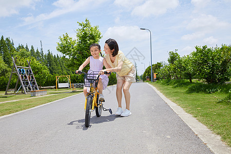 妈妈教小女孩骑单车背景图片