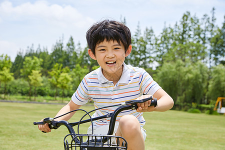 公园锻炼小男孩草坪上骑单车背景