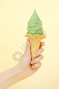 手握哈密瓜味奶油冰淇淋甜筒背景图片