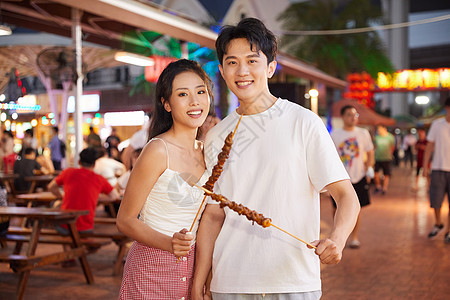 青年情侣逛夜市吃美食背景图片