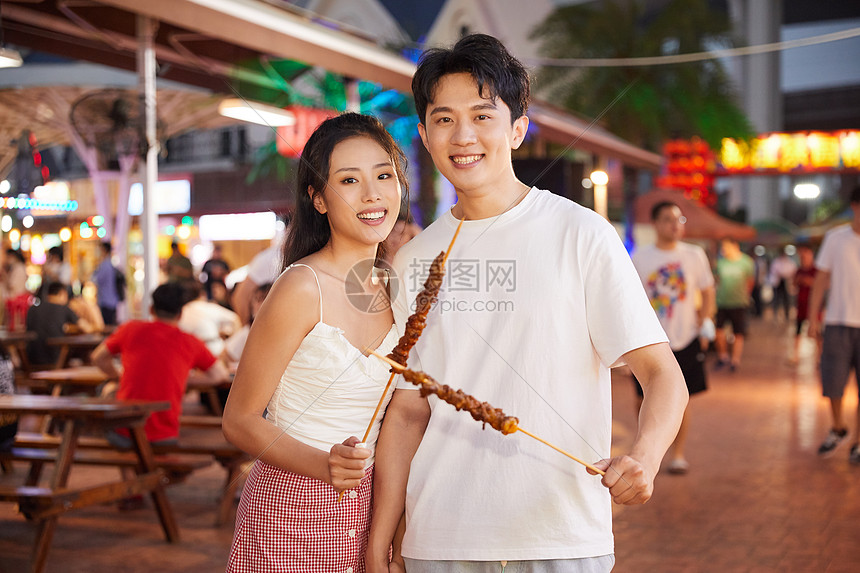 青年情侣逛夜市吃美食图片