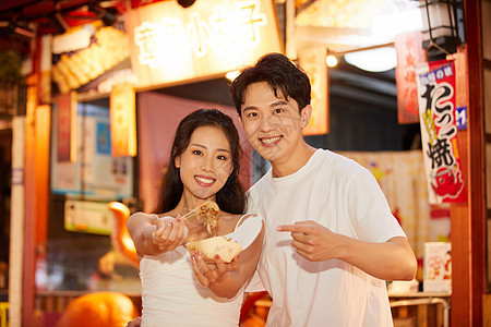 青年情侣逛夜市吃章鱼小丸子背景图片