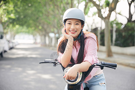 户外骑行美女户外骑电动车戴头盔背景