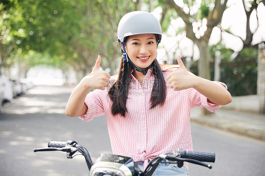 美女户外骑电动车戴头盔